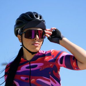 Femme cycliste regardant au loin avec lunettes de soleil, casquette et maillot de cycliste