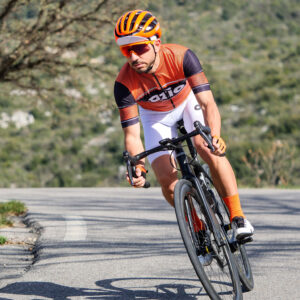 Cycliste homme route maillot vélo manches courtes orange et cuissard blanc virage