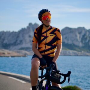Cycliste femme posant en bord de mer avec son maillot orange