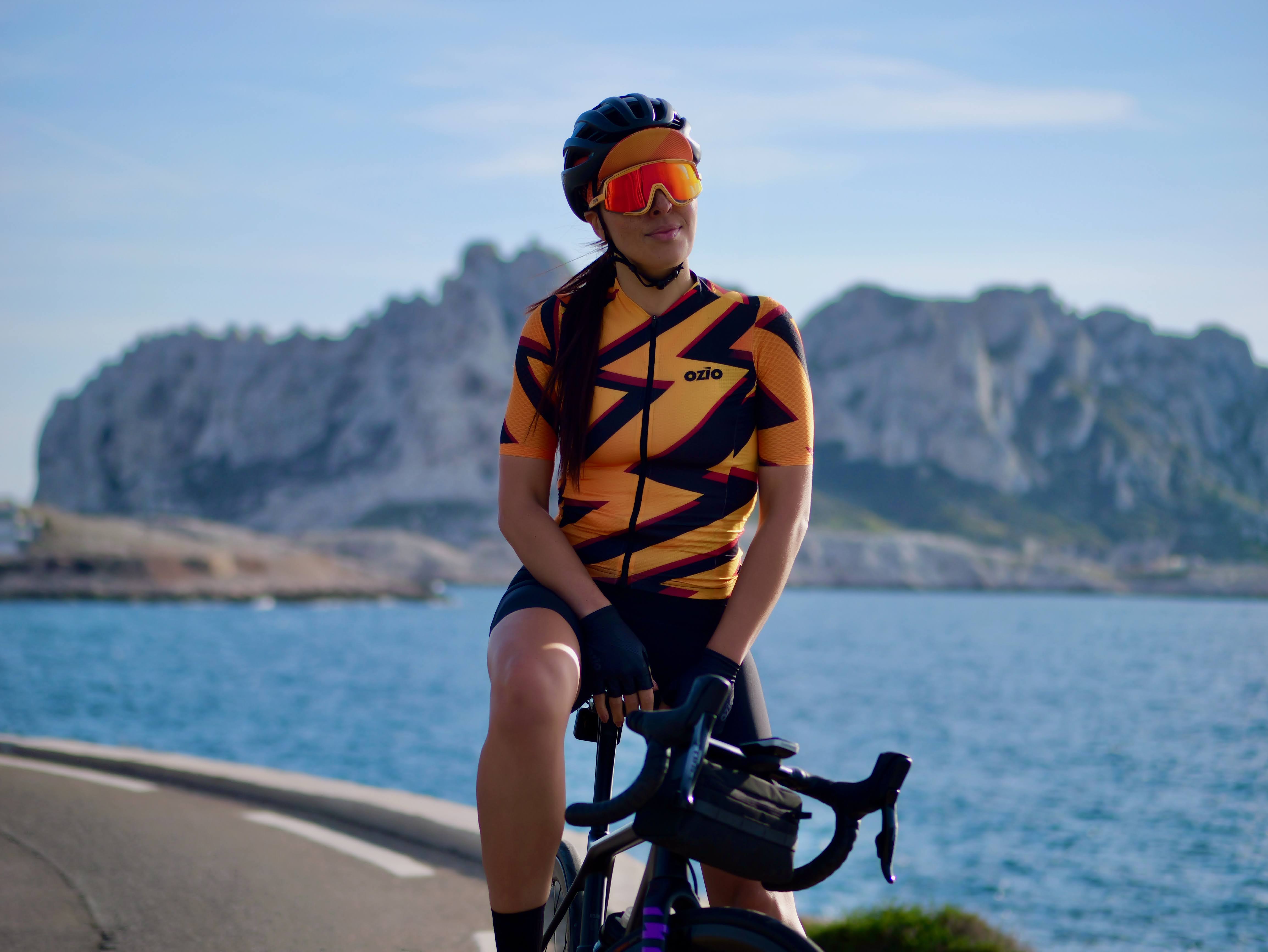 Cycliste femme posant en bord de mer avec son maillot orange