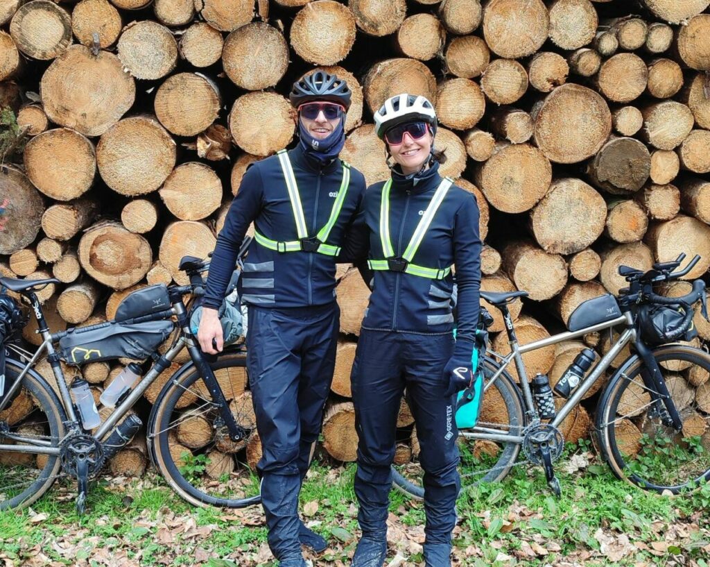 Cyclistes en voyage à vélo qui posent devant un tas de bois