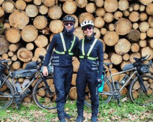 Cyclistes en voyage &agrave; v&eacute;lo qui posent devant un tas de bois